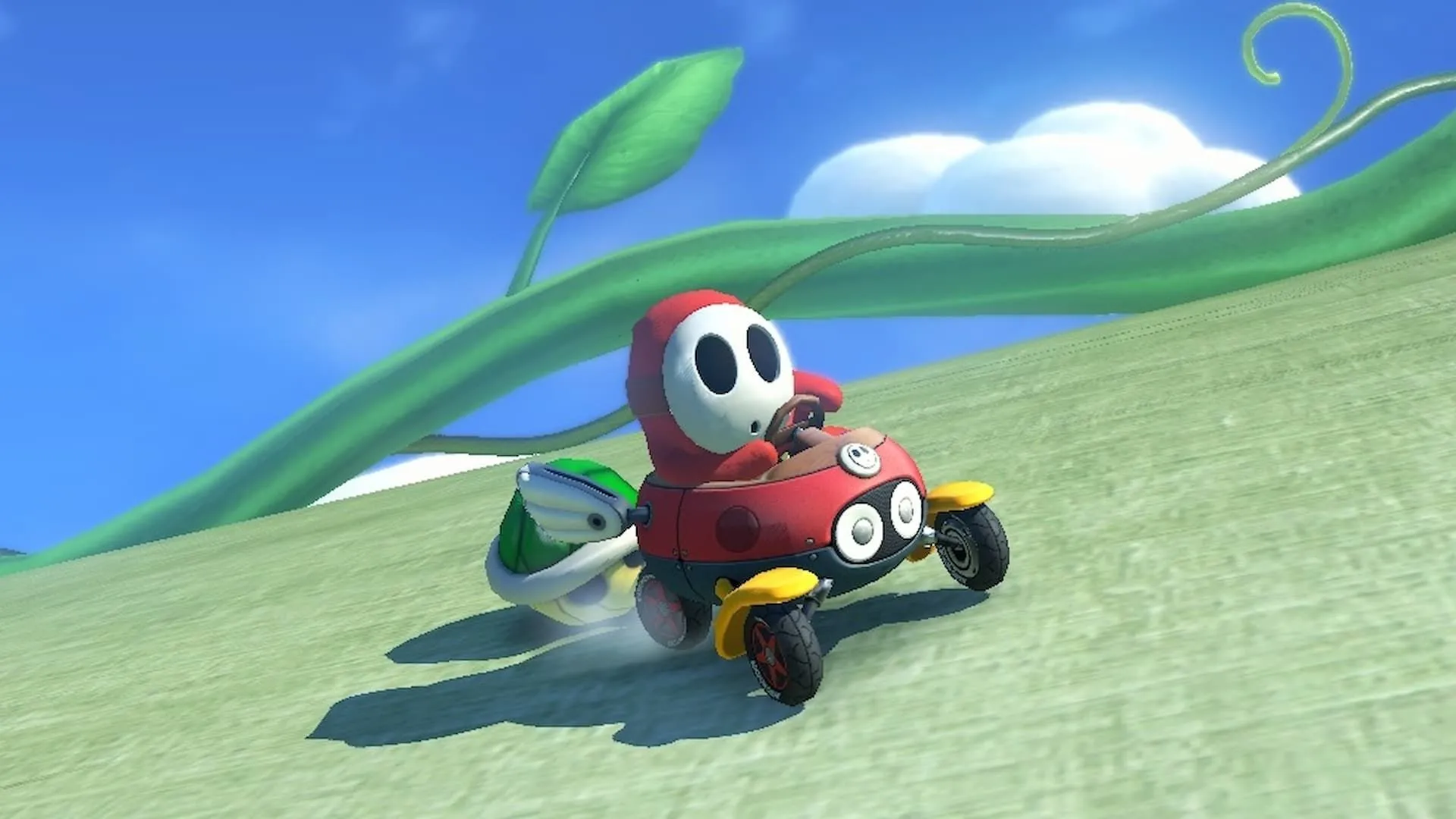 Shy Guy đỏ bị rượt đuổi bởi mai rùa xanh trong Mario Kart 8 Deluxe trên Nintendo Switch